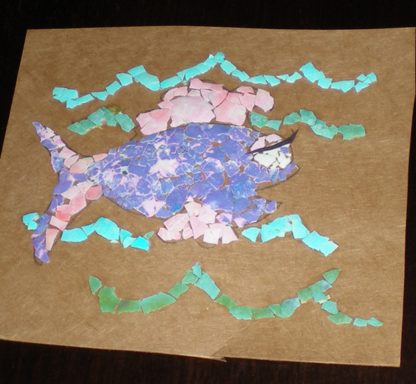 Eggshell mosaic of a fish with green and blue waves on brown cardstock