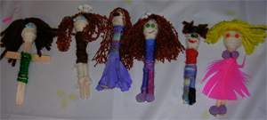 Row of handmade popsicle stick dolls with yarn hair and clothes